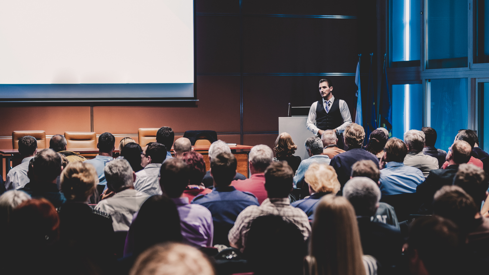 Professional keynote speaker giving a business presentation to a large audience at a conference event